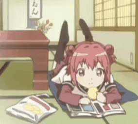 Pink-haired anime girl lying on floor reading book and blinking slowly while holding snack.
