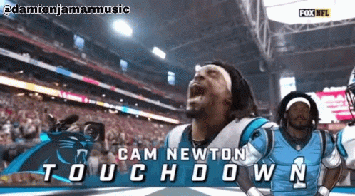 Football player celebrating touchdown with teammates in stadium.