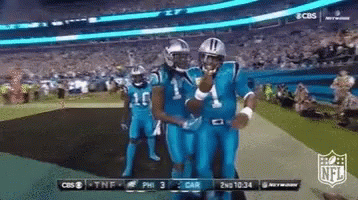 Football player fumbles ball during game, teammates and opponents react.