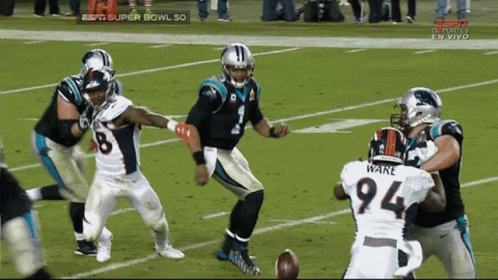 Football player diving forward during a tackle, ball rolls away.