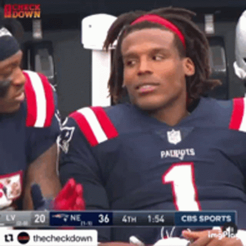 Football player in Patriots uniform laughing on bench with teammates.