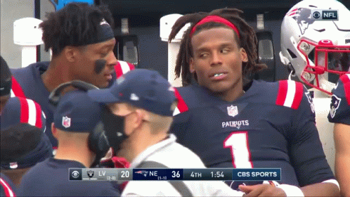 Football player reacting to fumble, teammates gather around him.