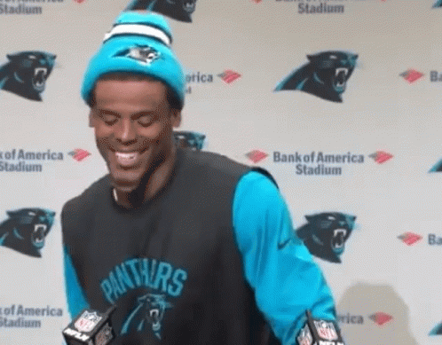 Man in Panthers gear smiling at press conference