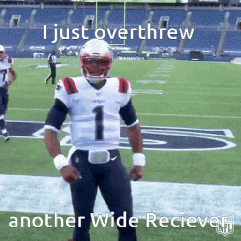 Football quarterback crossing arms on field with teammates nearby