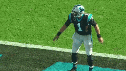 Football player in Panthers uniform doing a dance move with arms out and then bending forward.