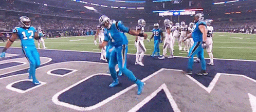 Football player in blue uniform celebrating with teammates on field.