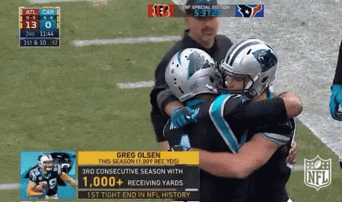 Football player being congratulated by teammates on the field.