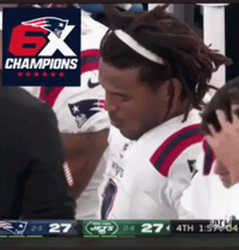Football player laughing and gesturing while seated on the bench.