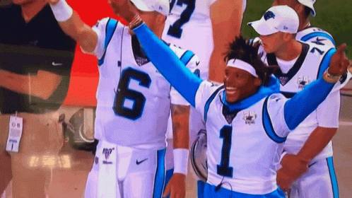 Football player number 1 celebrating with arms raised, surrounded by teammates.