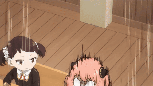 Two girls at desks; pink-haired girl looks up startled while writing, dark-haired girl stays calm.