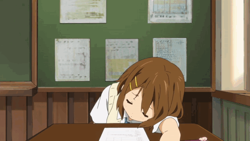 Girl at desk in classroom resting head on arms